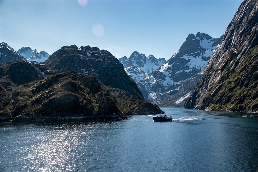 Boat heading up a mountain fjord between snowy peaks